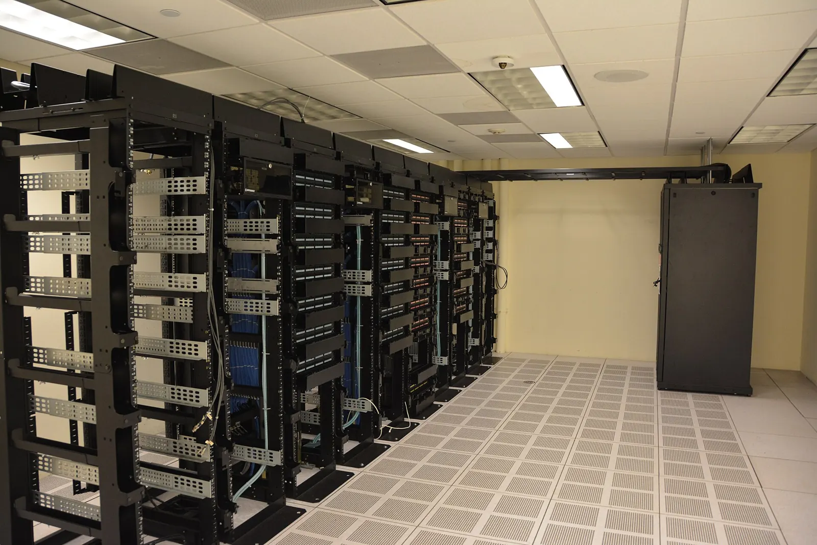 Rows of open server racks in a data hall — the physical reality behind every hosting plan.